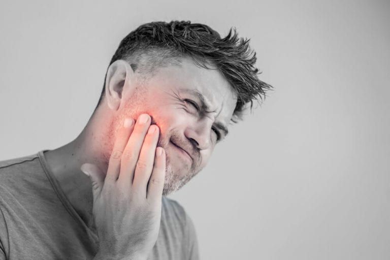 man holding his jaw in pain