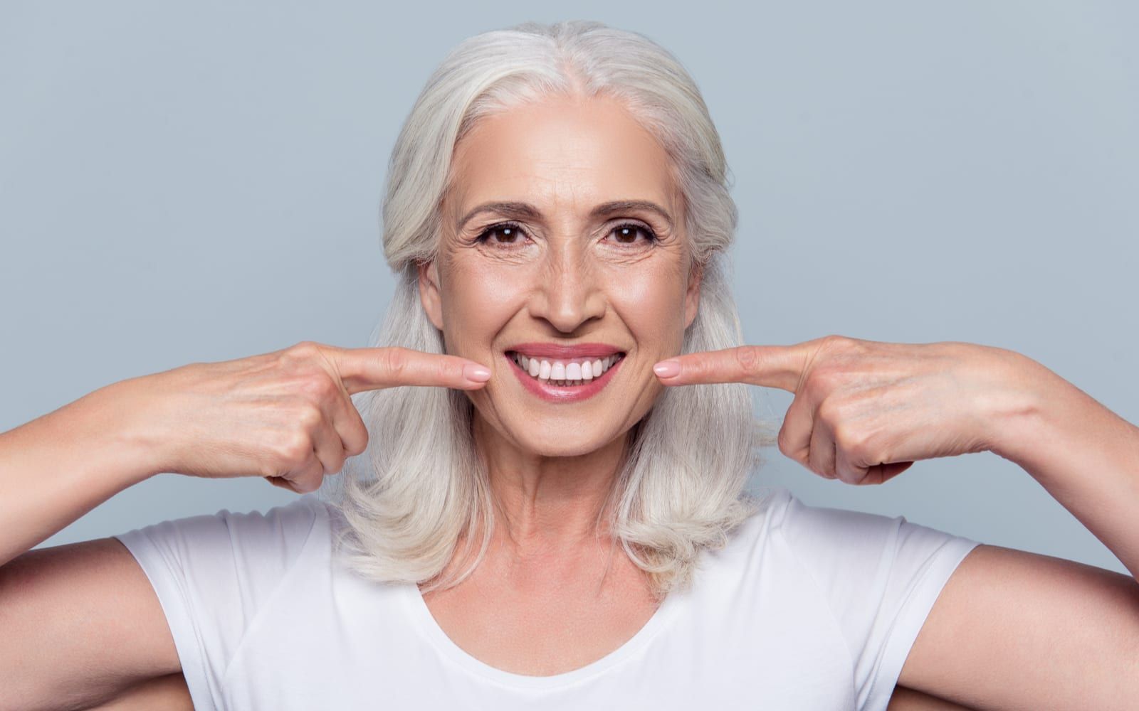 Smiling woman pointing at new dental implants