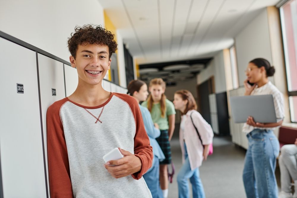 teenager smiling at school while holding phone
