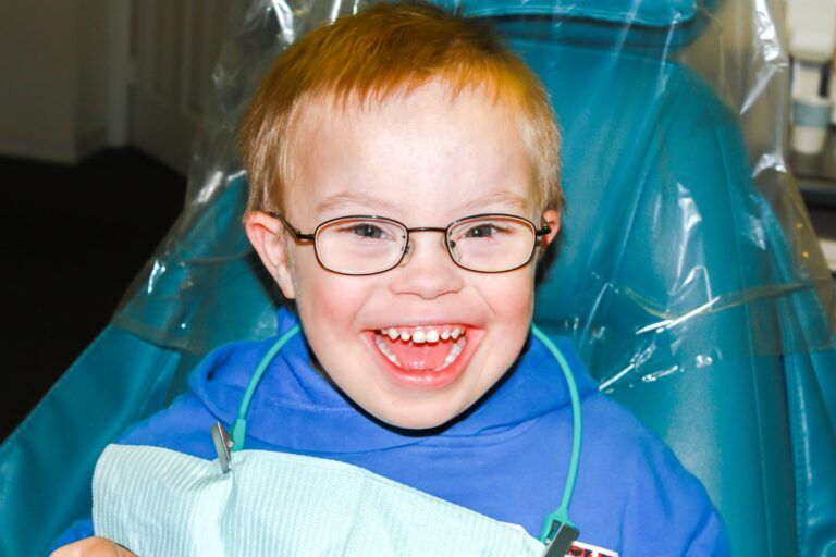 young boy with down syndrome smiling in dental chair