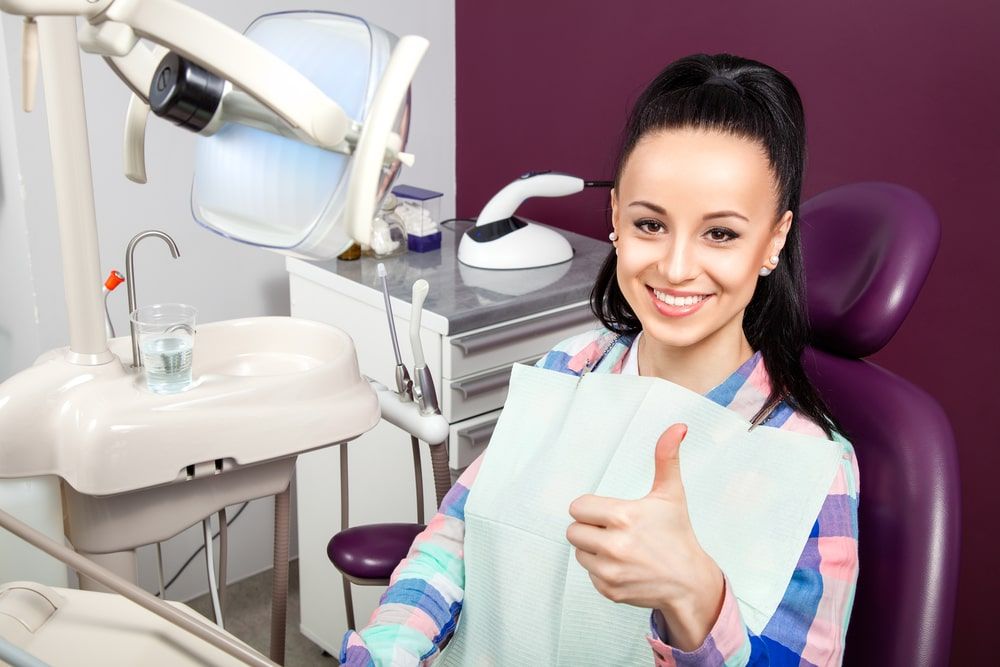 woman in dental chair with thumb up