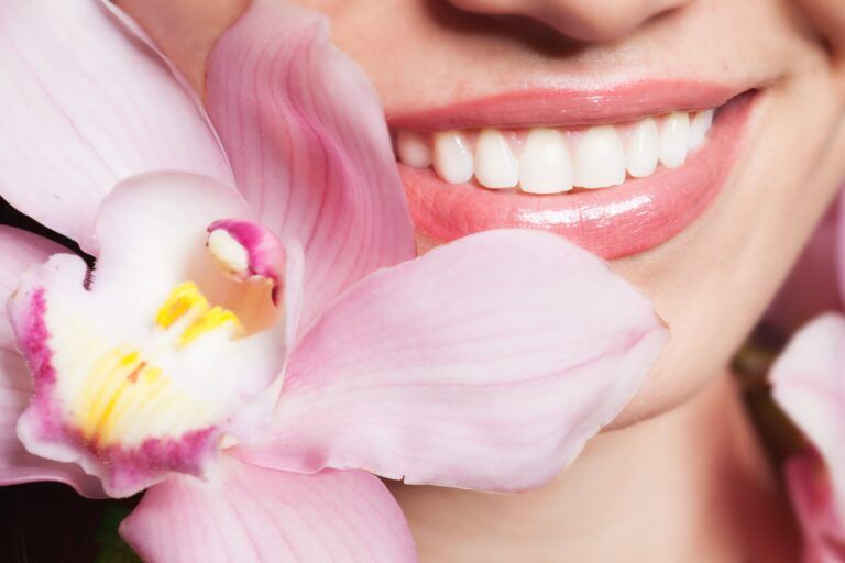 woman with pretty smile beside orchid blossom